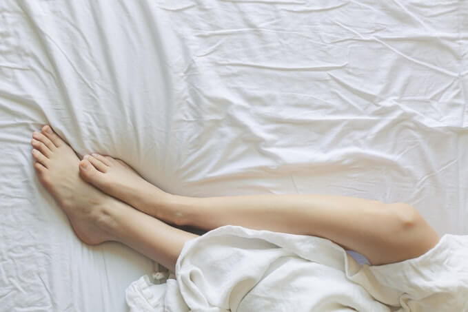 Pernas femininas envoltas num lençol branco